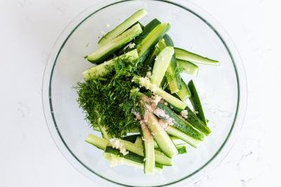 cucumbers in a bowl with dill and garlic and salt