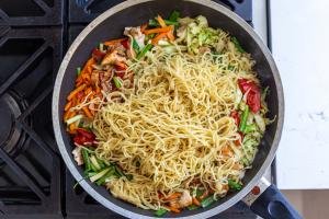 noodles in a skillet with veggies and chicken