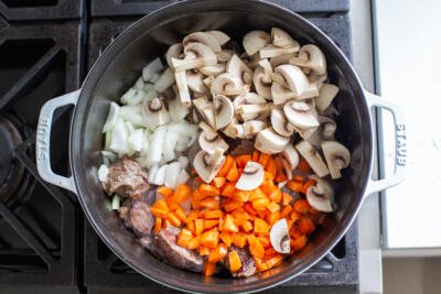veggies and mushrooms added to the pot with beef