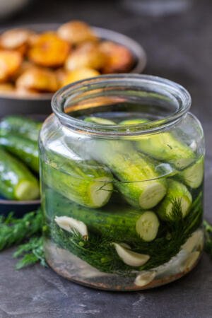 Quick pickled cucumbers in a jar with other pickles on a plate