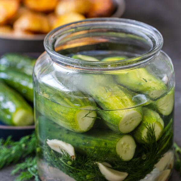 Quick pickled cucumbers in a jar with other pickles on a plate