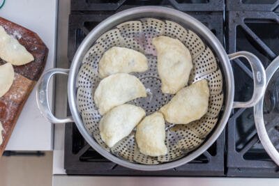 cooked pierogi in a pot with steamer