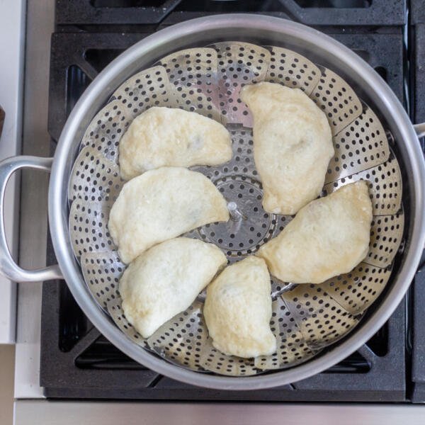 cooked pierogi in a pot with steamer