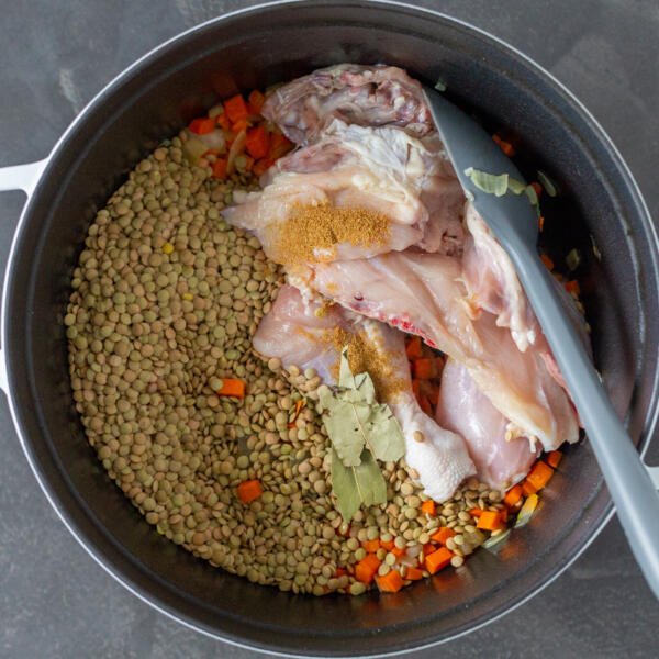 Lentil, chicken and veggies in a pot with bay leaves