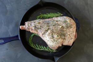 spiced leg of lamb with rosemary on a pan