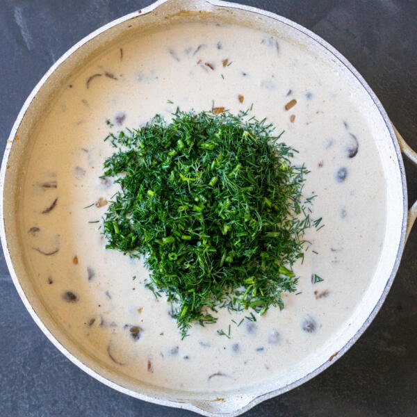 dill added to mushroom gravy in a pan