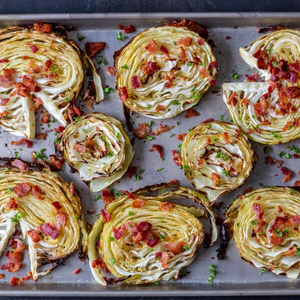 crispy roasted cabbage steaks on a pan with bacon