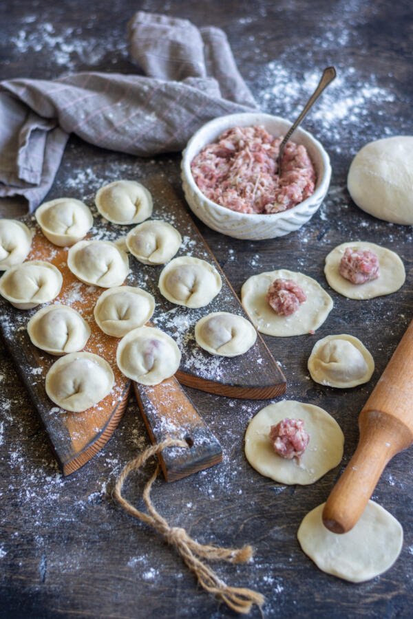 Pelmeni on a cutting board with meat being done