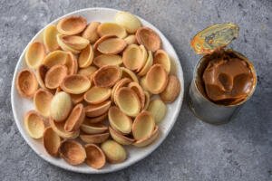 walnut cookie halves with a jar of dulce de leche