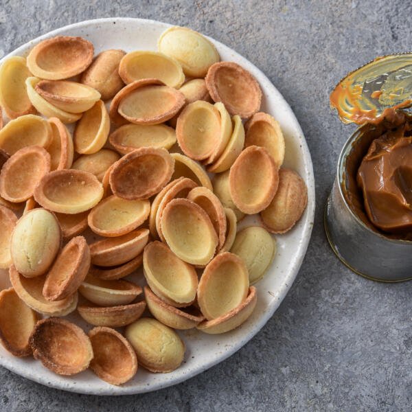 walnut cookie halves with a jar of dulce de leche