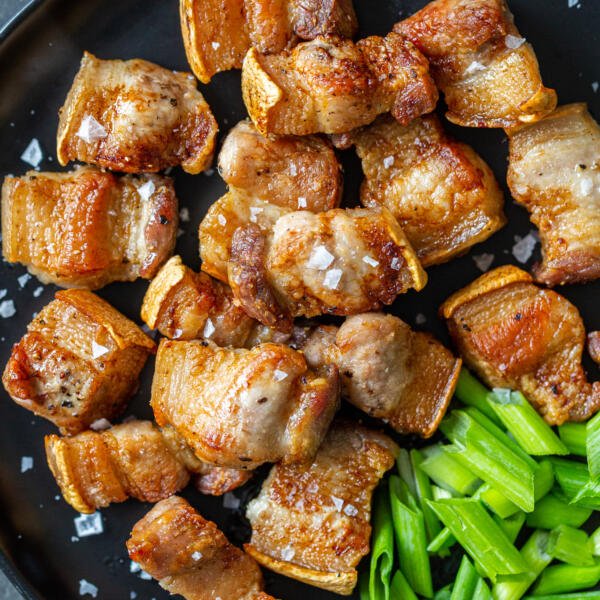 Pork belly bites on a plate with green onions