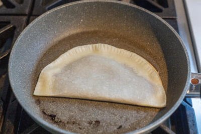 frying cheburek in a frying pan