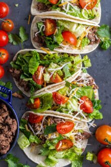 Ground beef tacos on a tray with veggies and meat on the sides