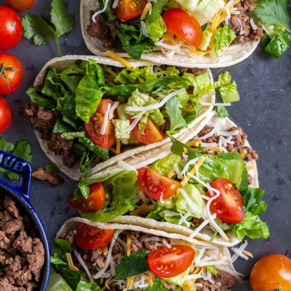 Ground beef tacos on a tray with veggies and meat on the sides