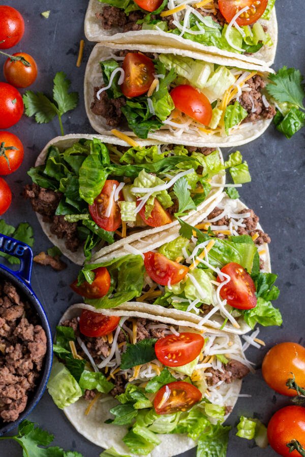 Ground beef tacos on a tray with veggies and meat on the sides