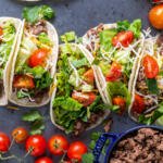 Ground beef tacos on a tray with veggies and meat on the sides