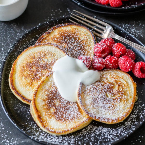Oladi with berries and sour cream on a plate