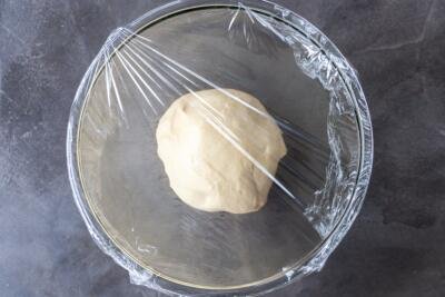 Challah Bread dough in a bowl covered with plastic