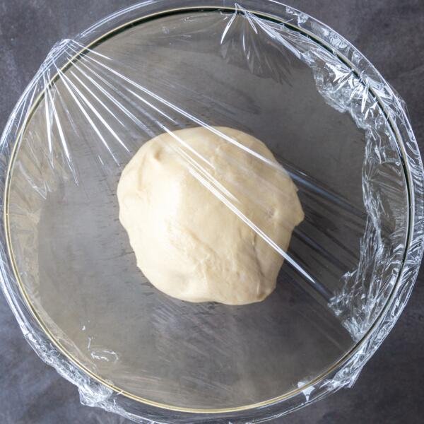 Challah Bread dough in a bowl covered with plastic