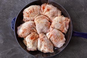 Seasoned chicken thighs in a pan