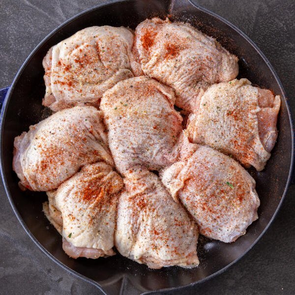 Seasoned chicken thighs in a pan