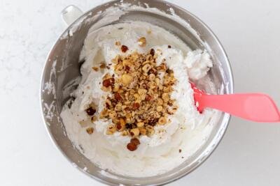 Whisked egg whites with hazelnuts added to the mixing bowl