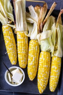 grilled corn on a tray with butter