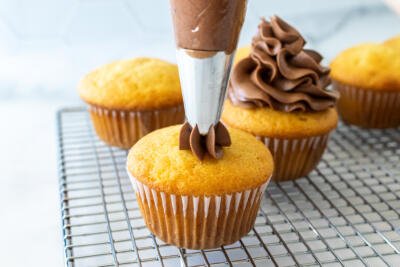 cream being piped onto a cupcake