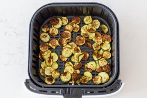 cooked zucchini in an air fryer basket