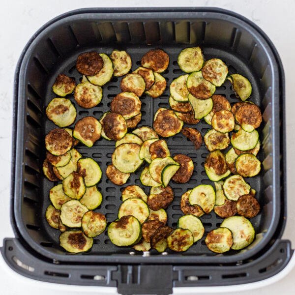 cooked zucchini in an air fryer basket