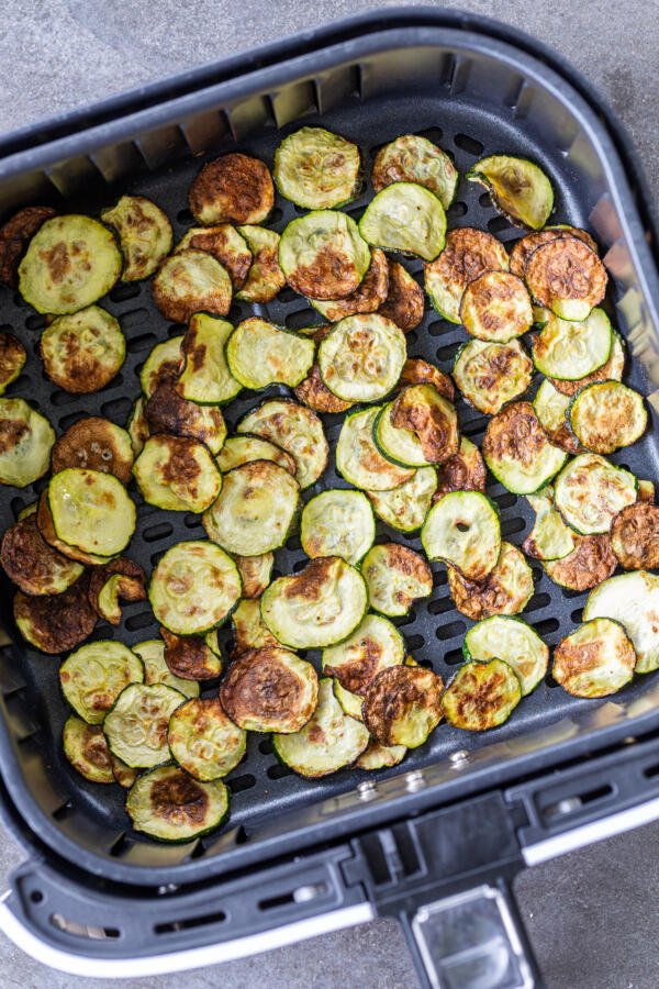 cooked zucchini in an air fryer basket