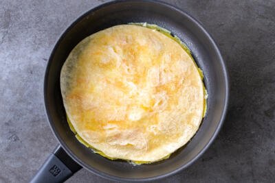 Tortilla on top of eggs in a pan
