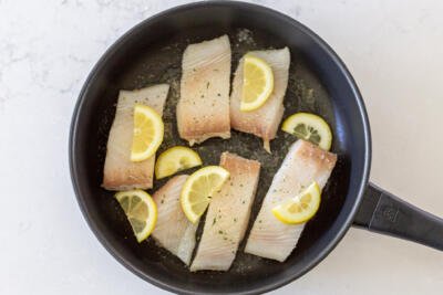 halibut with lemon and seasoning in a pan