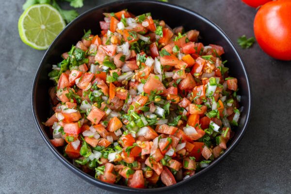 The Classic Pico de Gallo in a bowl with vegetables next to it