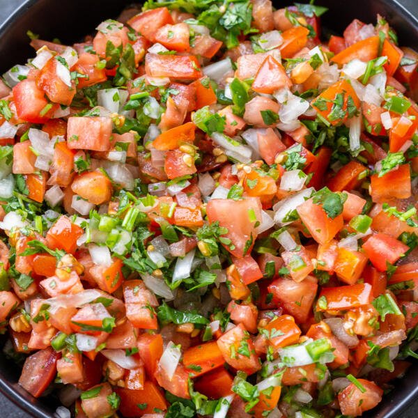 The Classic Pico de Gallo in a bowl with vegetables next to it