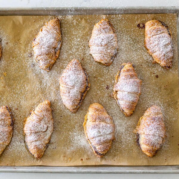 croissants with powdered sugar on a baking sheet