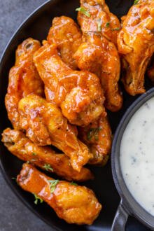 air fryer wing with buffalo sauce on a plate with ranch for dipping