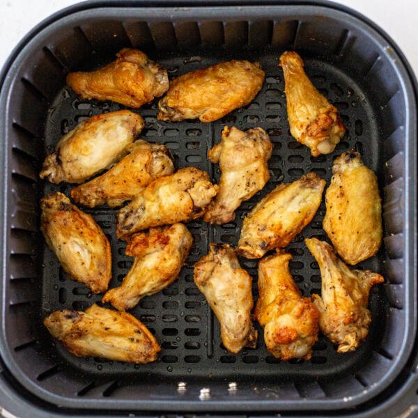 Cooked chicken wings in an air fryer basket