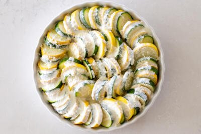 Lined zucchini and squash and sauce in a baking pan