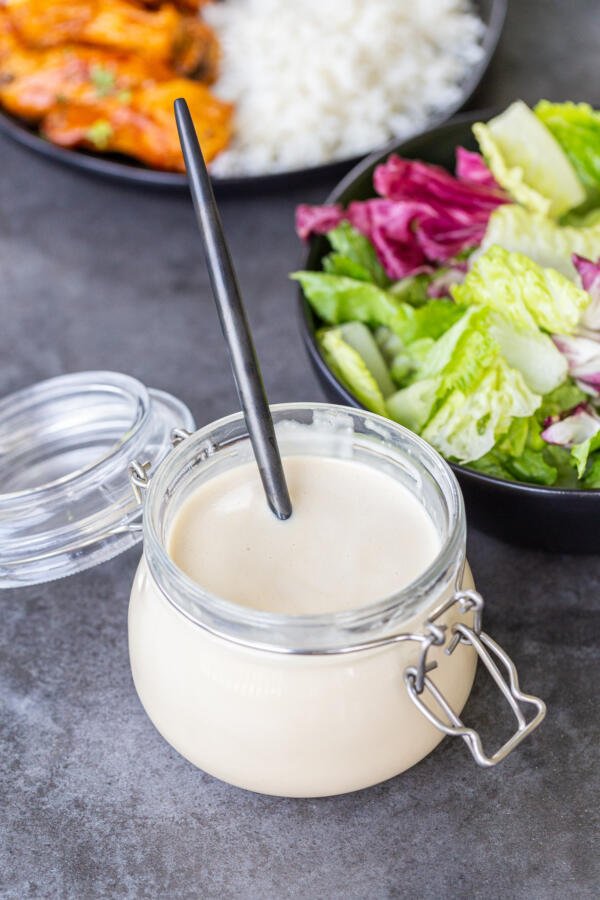 China Coast Salad dressing in a jar with a spoon, salad next to it