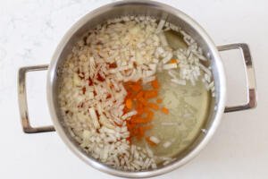 onions, carrots and rice in a pot with water