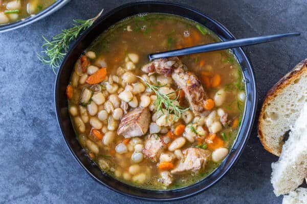 a bowl of white bean soup in a bowl with bread next to it