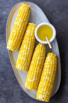 cooked corn on a cob with butter on a plate