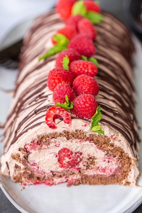 Decorated Raspberry chocolate cake roll on a plate.