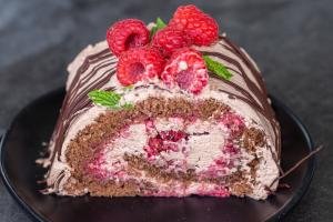 A slice of Decorated Raspberry chocolate cake roll on a plate.