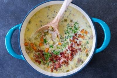 Chowder in a pot with green onion and bacon.