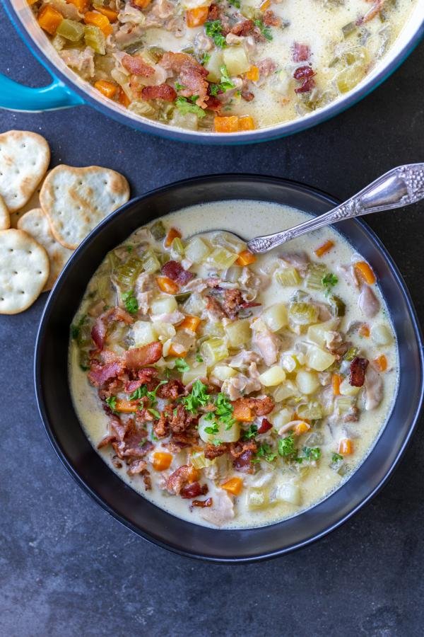 Clam Chowder in a bowl with bacon and herbs.