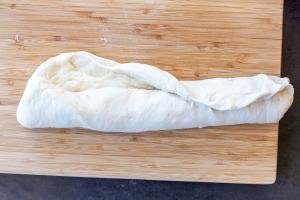 Rolled up bread dough on a cutting baord