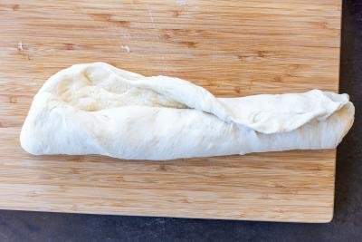 Rolled up bread dough on a cutting baord
