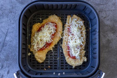 Chicken parmesan with marinara and cheese in an air fryer basket